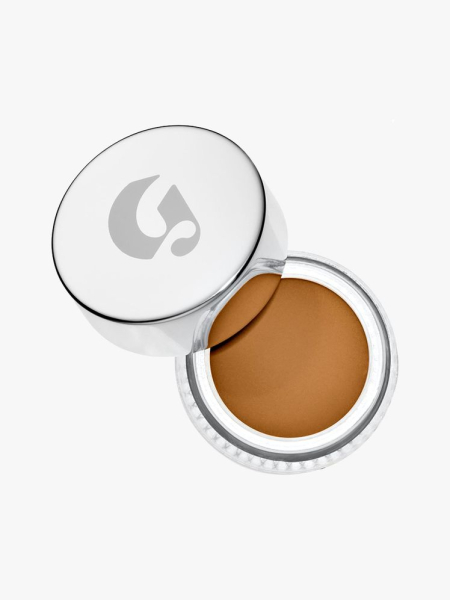 Glossier Stretch Concealer top view of a jar of concealer with silver cap ajar on light gray background